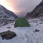 A green tent pitched in snowy mountains