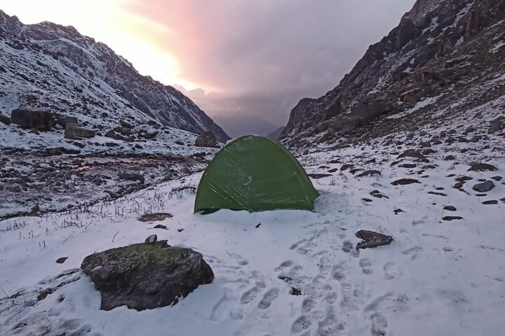A green tent pitched in snowy mountains