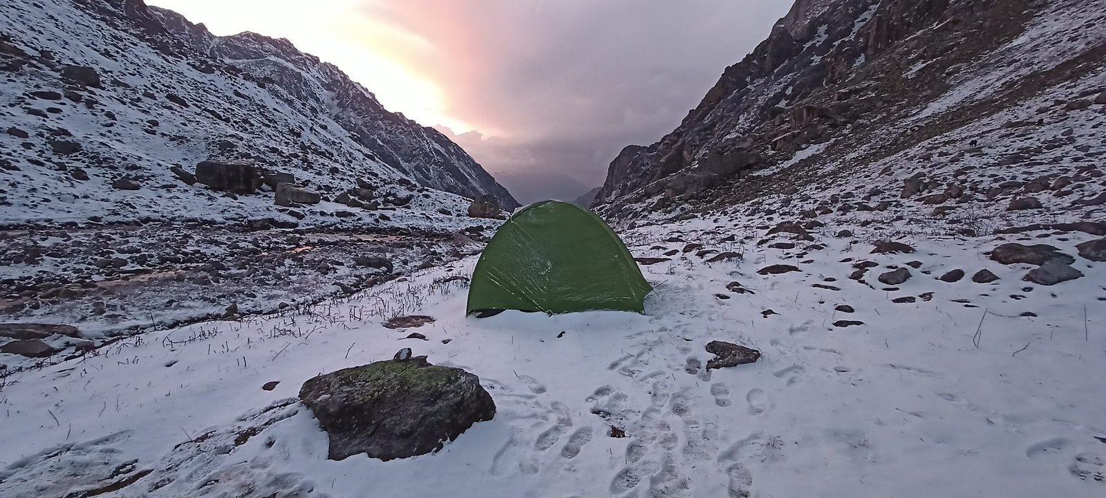 A green tent pitched in snowy mountains