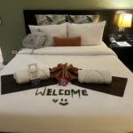 A neatly arranged hotel room bed with a white bedspread and large pillows