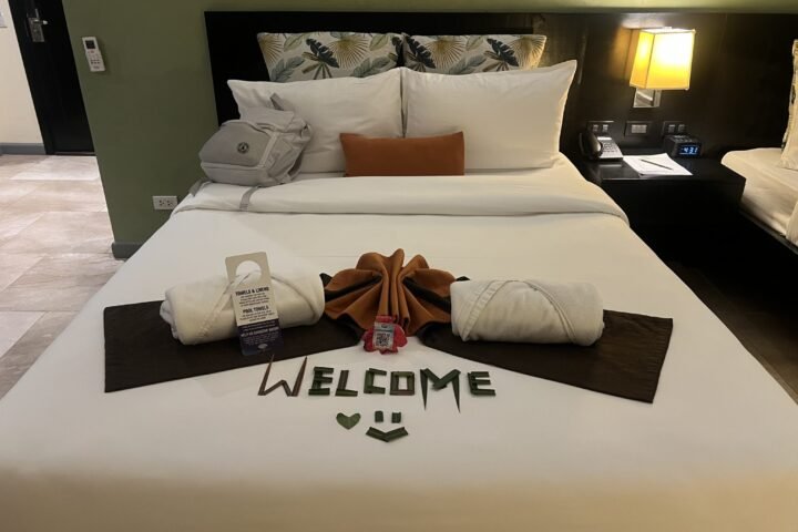 A neatly arranged hotel room bed with a white bedspread and large pillows