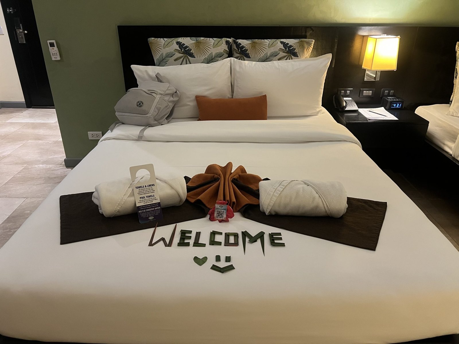 A neatly arranged hotel room bed with a white bedspread and large pillows
