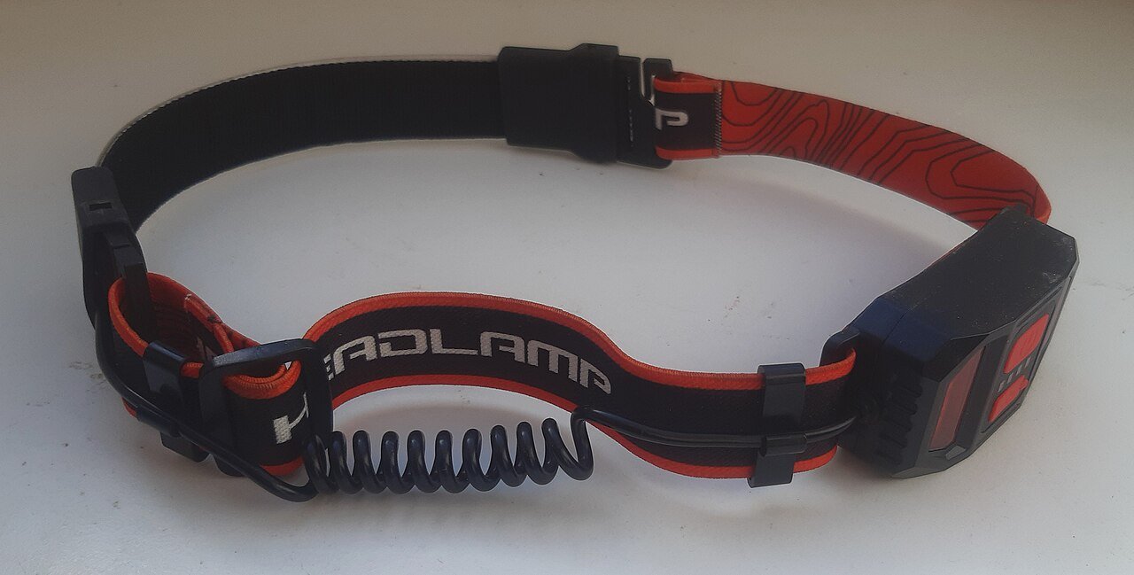 LED headlamp with a head strap and a coiled cable