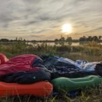 Sleeping setup in front of a sunset beside a river on a bike tour