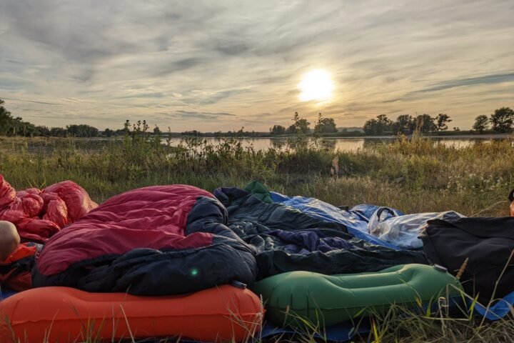 Sleeping setup in front of a sunset beside a river on a bike tour