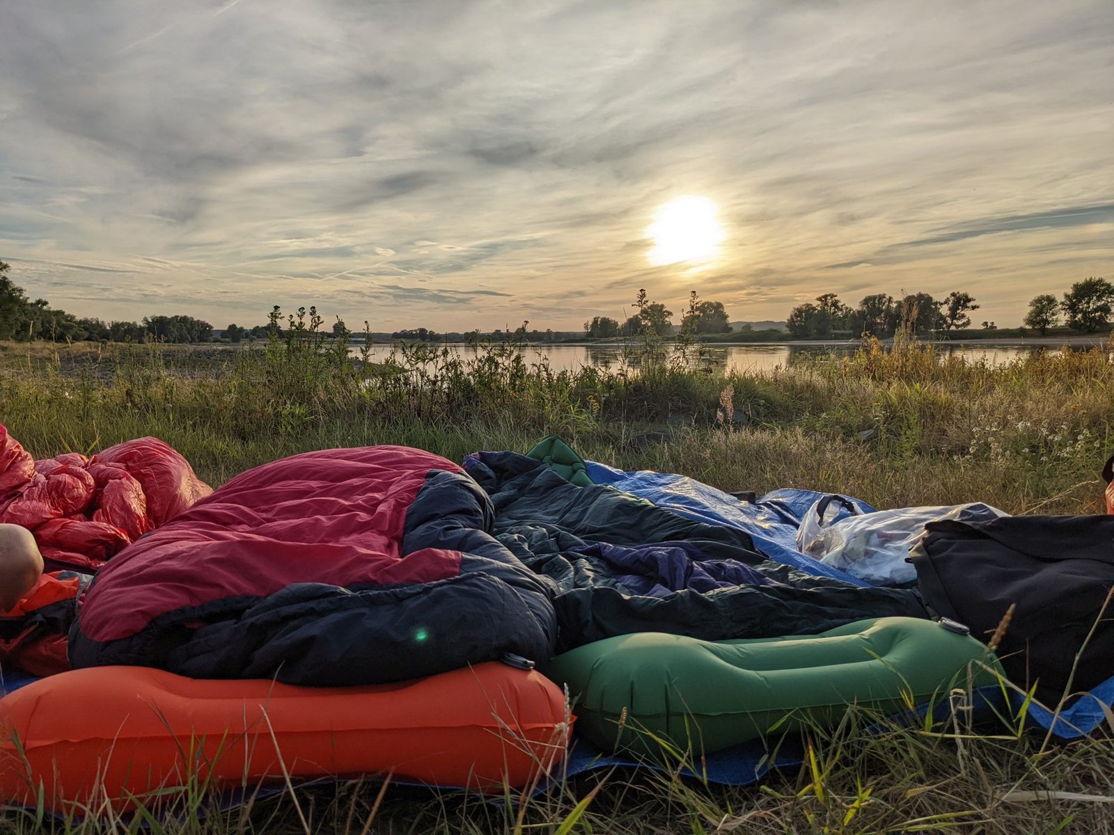 Sleeping setup in front of a sunset beside a river on a bike tour