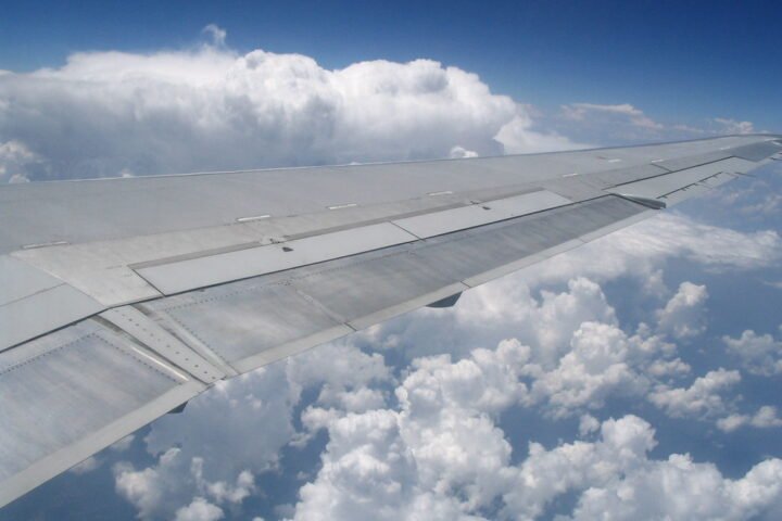 An airplane wing in front of cumulus clouds