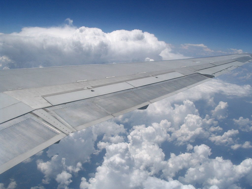 An airplane wing in front of cumulus clouds