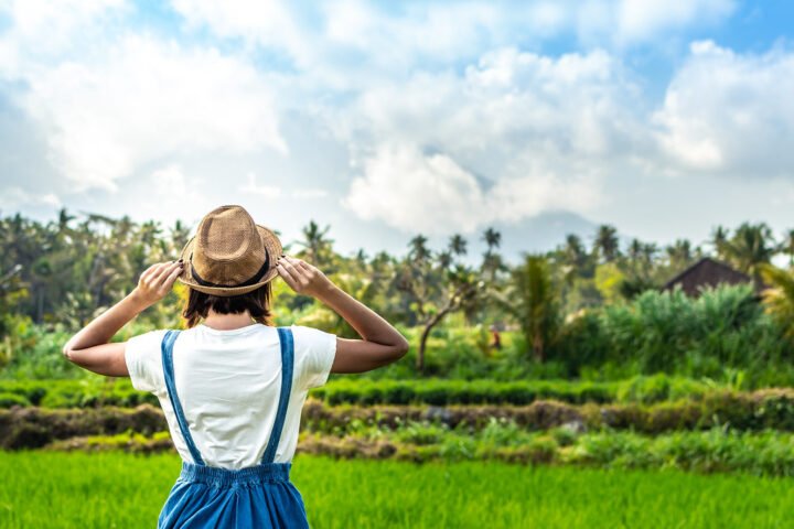 Smiling woman tourist in a straw hat with a mountain behind her in Bali