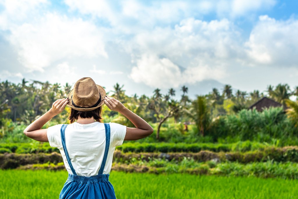 Smiling woman tourist in a straw hat with a mountain behind her in Bali