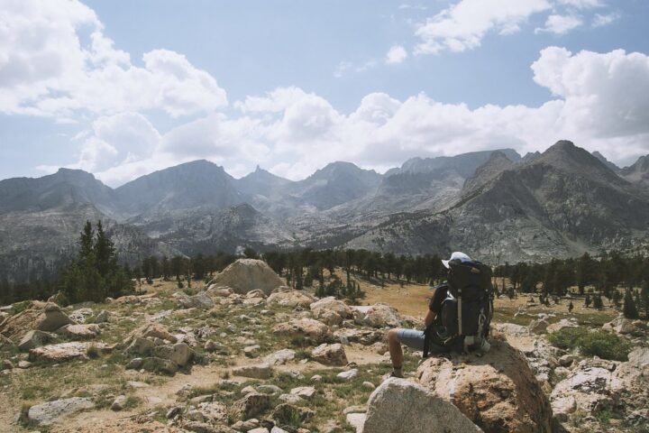 A hiker with a backpack sitting on a rock overlooking mountains