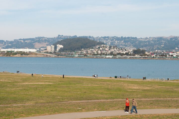 People walking in a park in front of a bay and the Berkeley shoreline